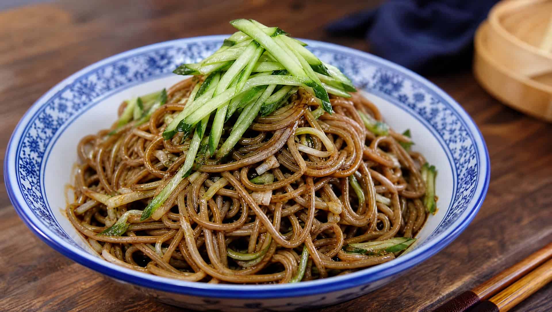Qiao-mian hele — chilled buckwheat noodles pressed through a hele press, dunked in sour-spicy vinegar broth