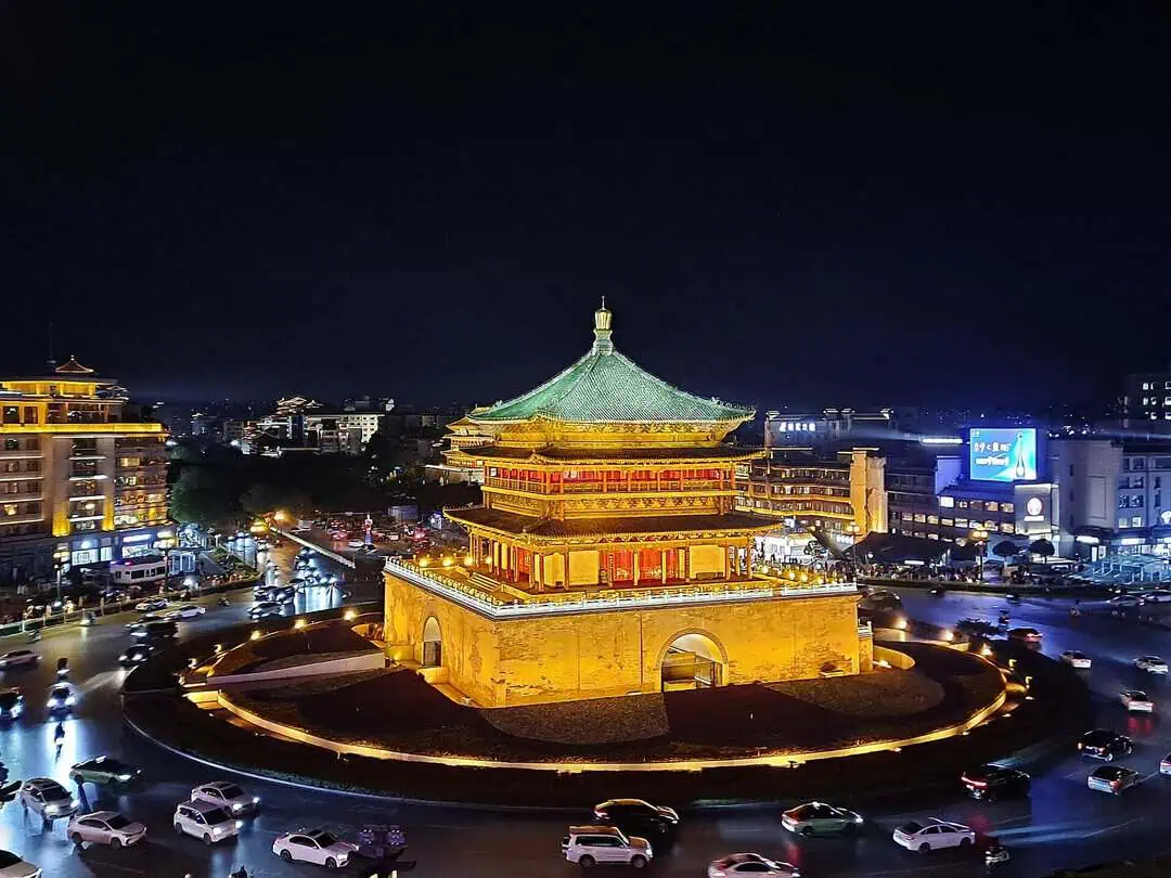 Xi'an Bell Tower illuminated gold at night, traffic circling below