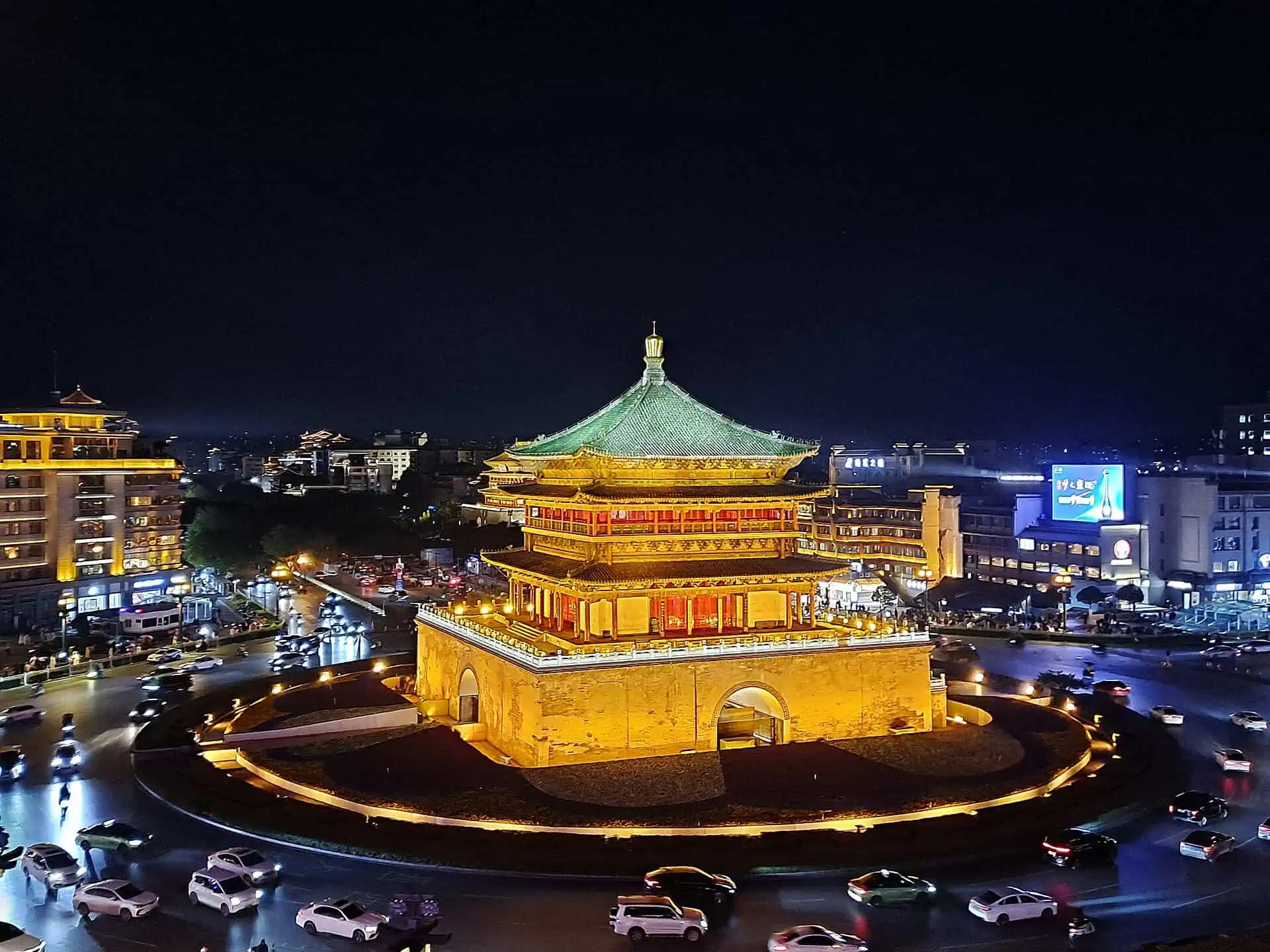 Xi'an Bell Tower illuminated gold at night, traffic circling below