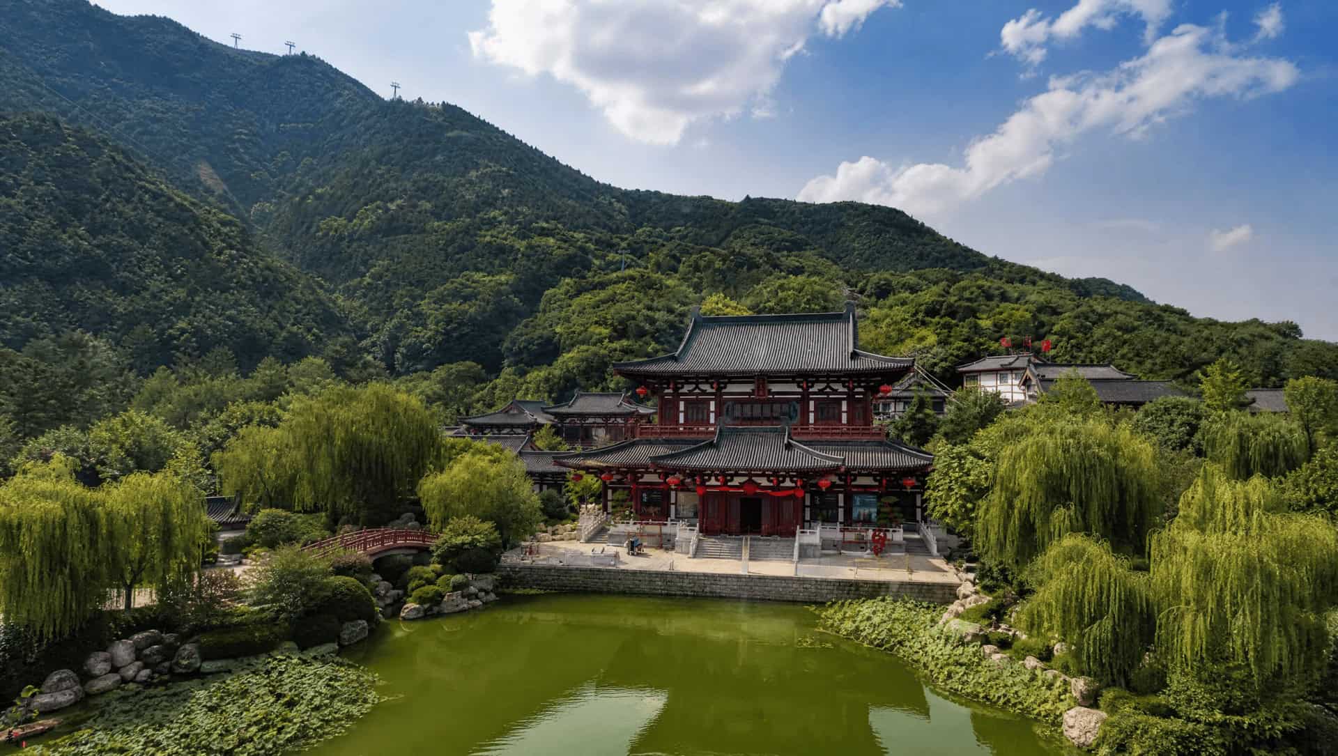 Huaqing Palace's halls and lake spread below Mount Li at dusk