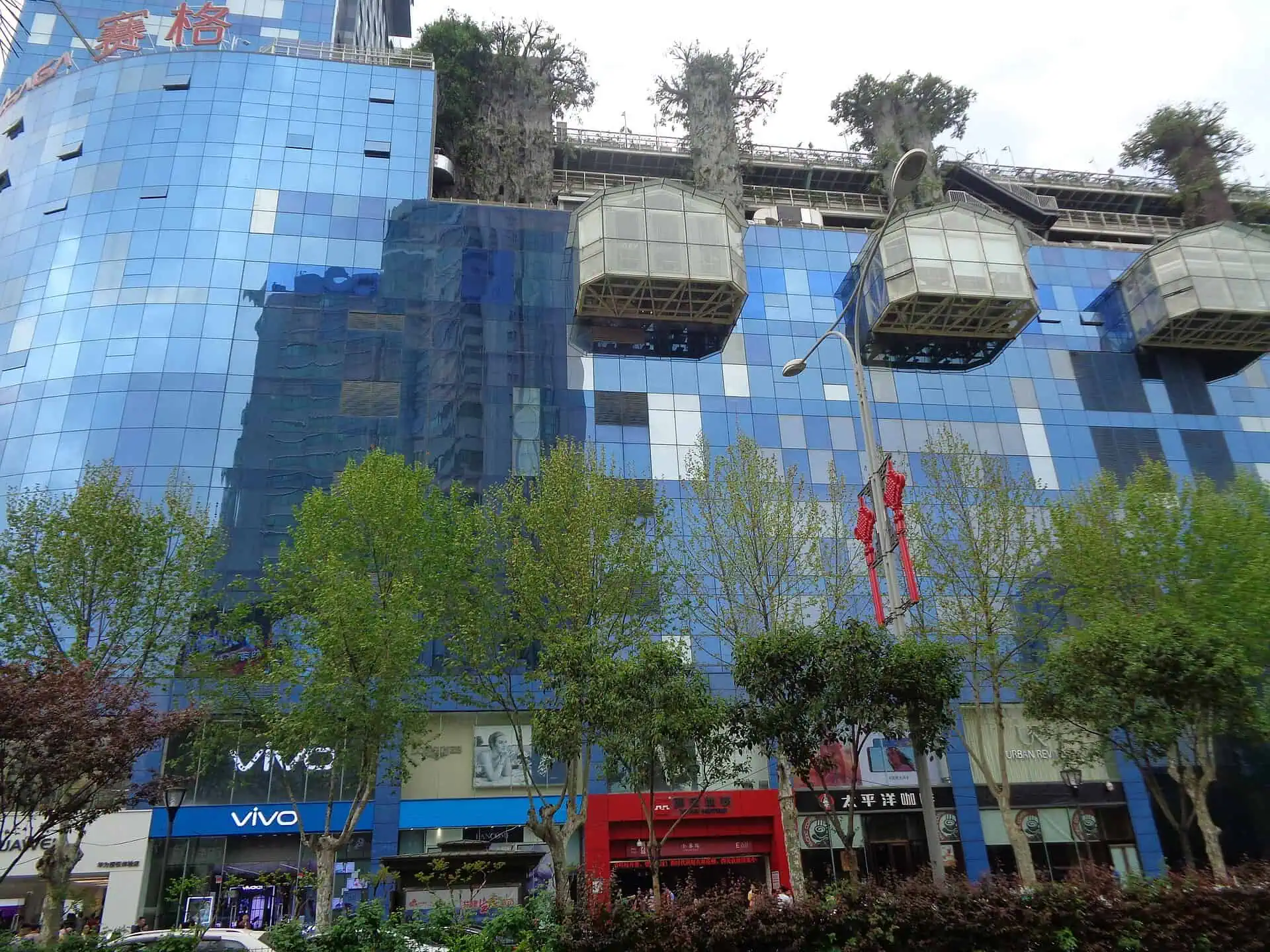 Blue glass facade and cantilevered pods of Saige International Shopping Center in Xiaozhai, Xi'an